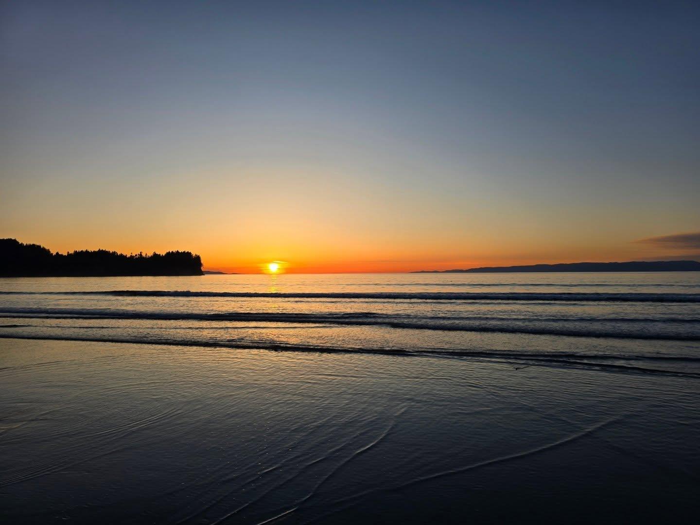 Photograph of the sun setting over the Strait of Juan de Fuca, the water dark and calm